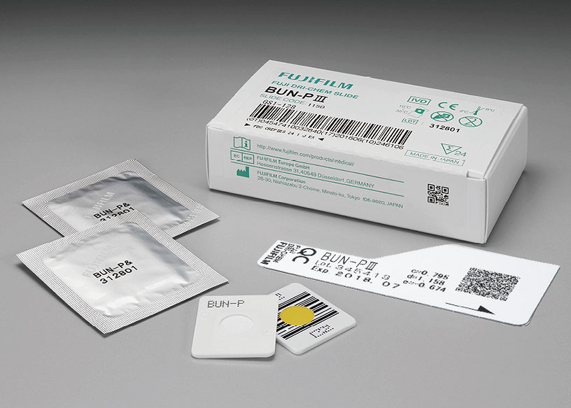 [foto] Caixa de lâminas BUN-P Ⅲ DRI-CHEM com duas lâminas enroladas em papel alumínio, duas lâminas sem embalagem (vista frontal e traseira) e cartão QC