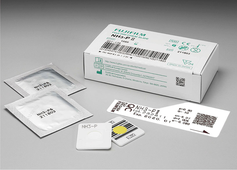 [foto] Caixa de lâminas NH3-PⅡ DRI-CHEM com duas lâminas enroladas em papel alumínio, duas lâminas sem embalagem (vista frontal e traseira) e cartão QC