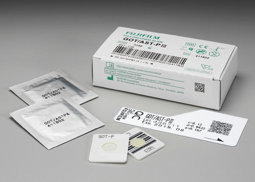 [foto] Caixa de lâminas GOT/AST-P Ⅲ DRI-CHEM com duas lâminas enroladas em papel alumínio, duas lâminas sem embalagem (vista frontal e traseira) e cartão QC