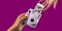 [photo] Main donnant un appareil photo INSTAX rose avec impression photo sur le côté à une autre main qui l'atteint