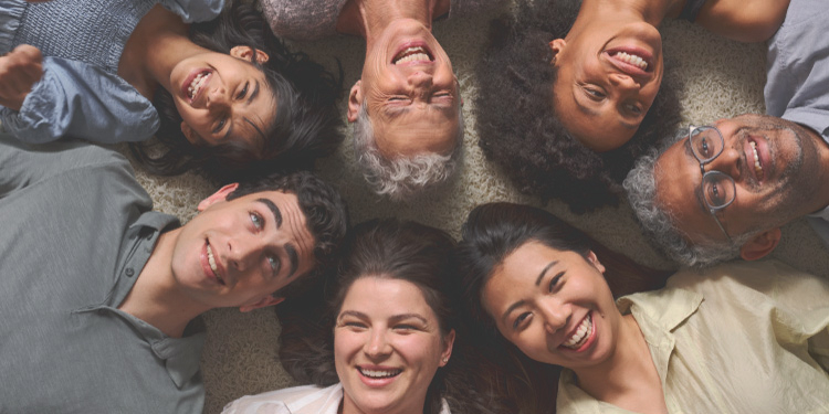 多様な人々が笑顔で集い、寝転んで上を見上げている様子