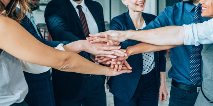 円陣を組んで手を重ねるビジネスパーソンたち