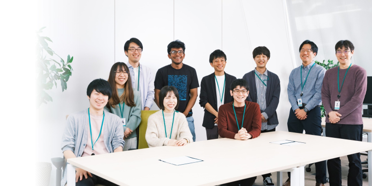 会議室で一緒に並んで座る部署のメンバーの集合写真