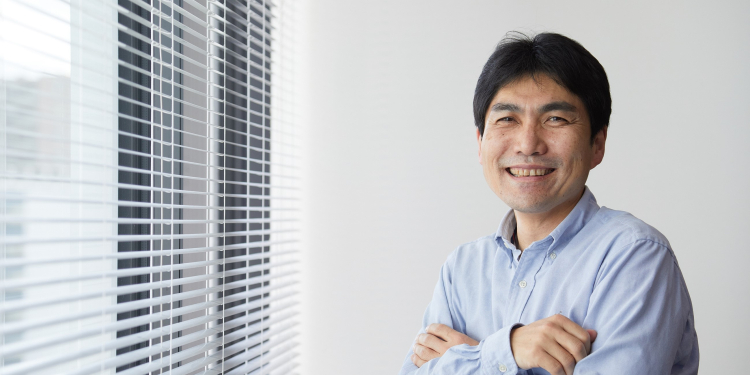 窓のそばで腕を組む社長