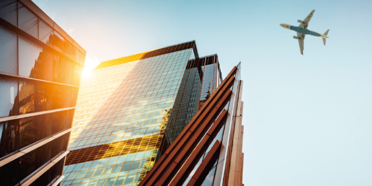 夕日に映えるガラス張りの高層ビルと飛行機