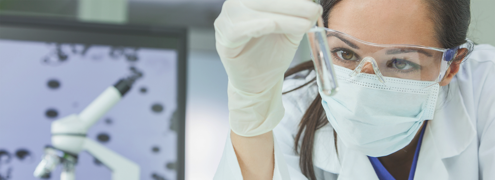 透明の液体が入った試験管を確認する女性の研究者