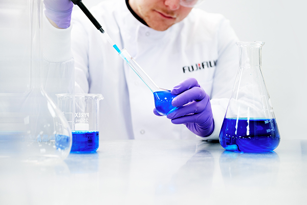 マイクロピペットでフラスコからインクを取り分ける白衣を着た男性