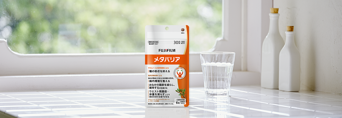 光が差し込む窓際に置かれたサプリメントと水の入ったグラスとボトル