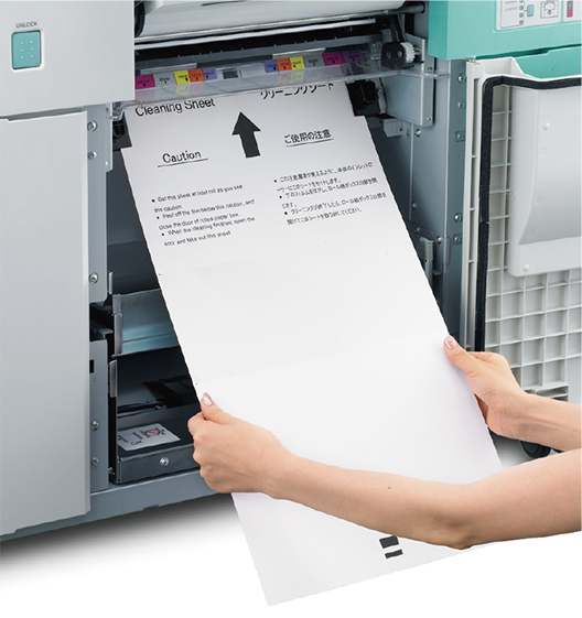 [photo] Woman feeding a cleaning sheet of paper into the paper feed of printer