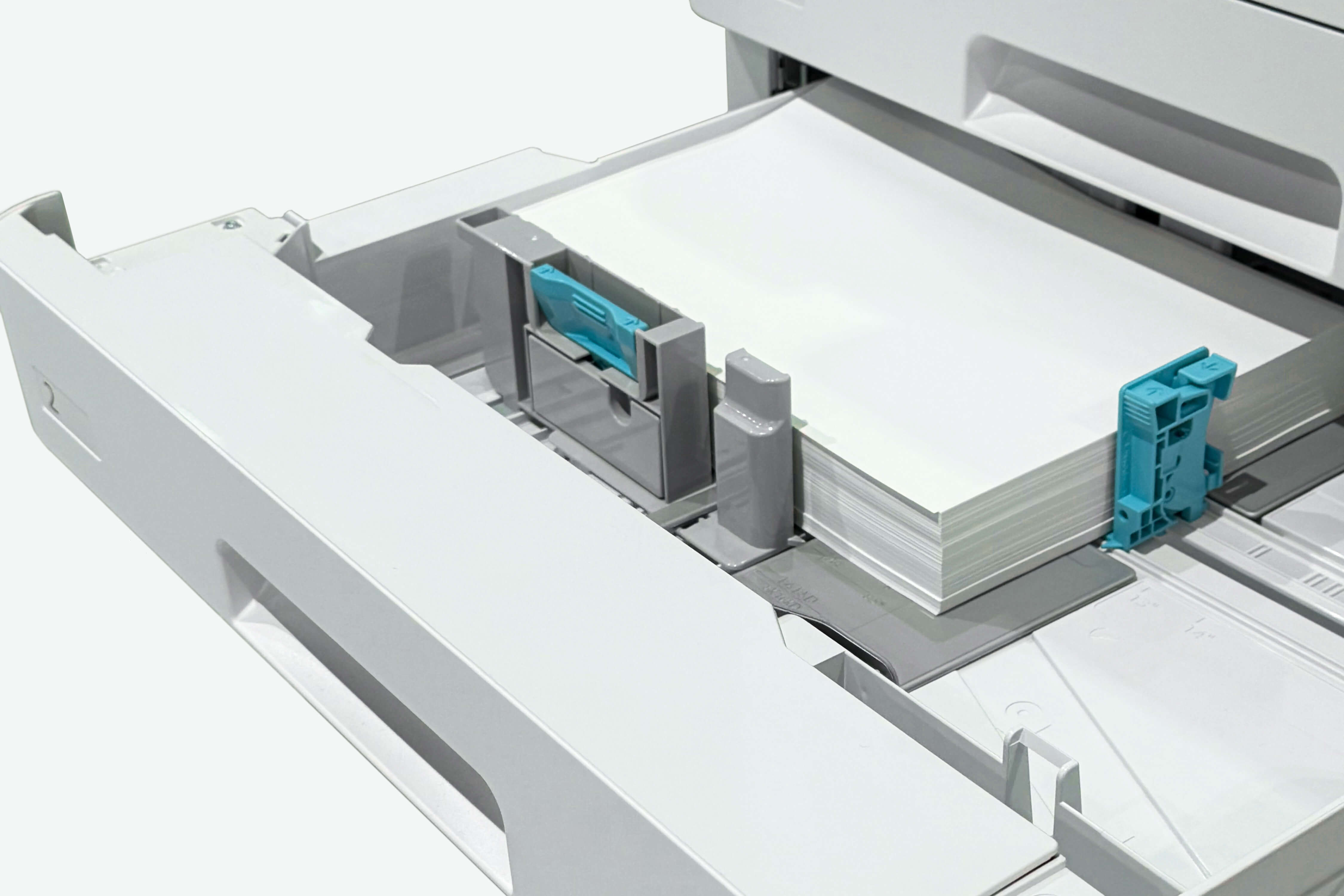 A stack of white paper set in the paper tray of a multifunction printer.
