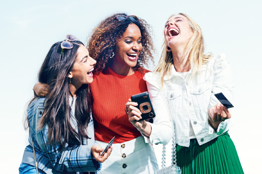 [photo] 3 female friends laughing while holding Instant Mini LiPlay and photo prints