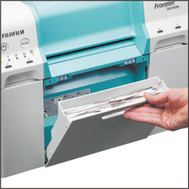 [photo] Hand pulling discharge scrap paper tray out of front of DE100