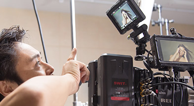 [photo] A cameraman pointing to the external monitor display of a digital camera he's looking at