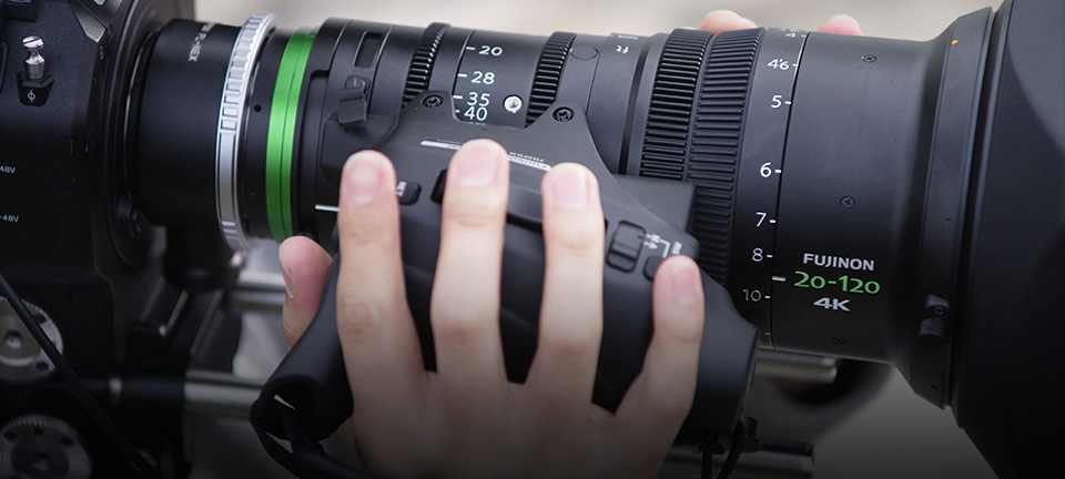 [photo] A cameraman's fingers on zoom buttons attached to an XK Series lens