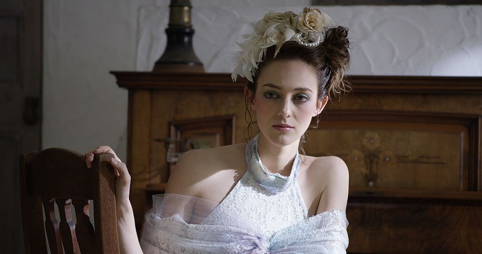 [photo] A medium view of a lady in a dress sitting on a chair