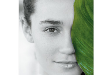 Image of a woman behind a large green leaf with Green Partial filter applied where everything except the leaf are black and white