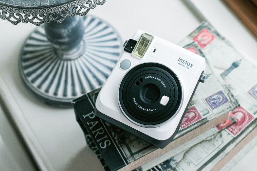 White mini 70 camera on top of the book on the side table