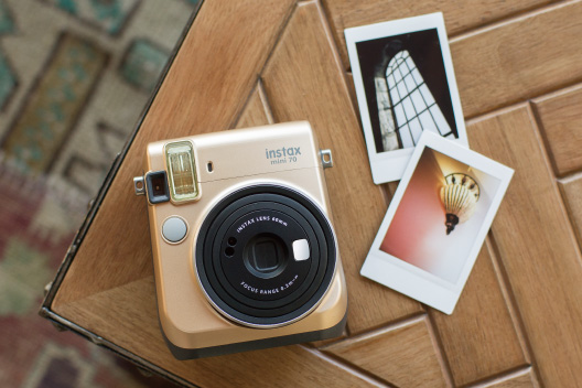 Stardust Gold mini 70 camera on the wooden table with two photos