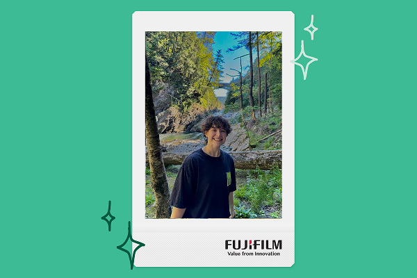 a woman poses in front of a river within an instax print frame