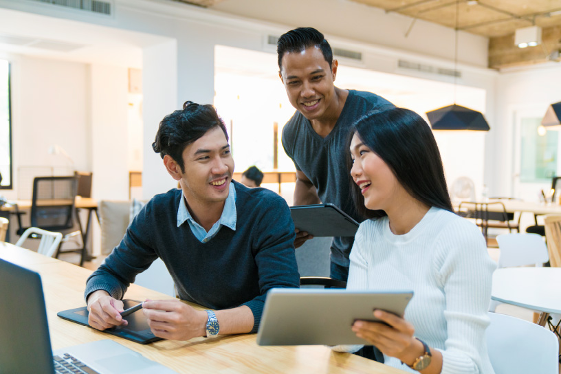 three people chatting while holding tablets in an office