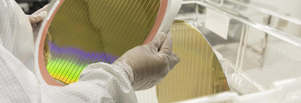 Hands of Engineer in white gloves holding a Silicon wafers