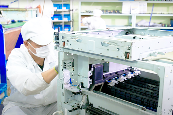 Workers checking a dismantled multifunction machine.