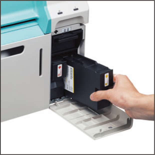 [photo] Hand putting ink cartridge replacement into ink slot of DE100 printer