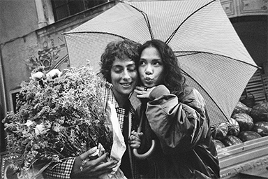Two people standing close together under an umbrella